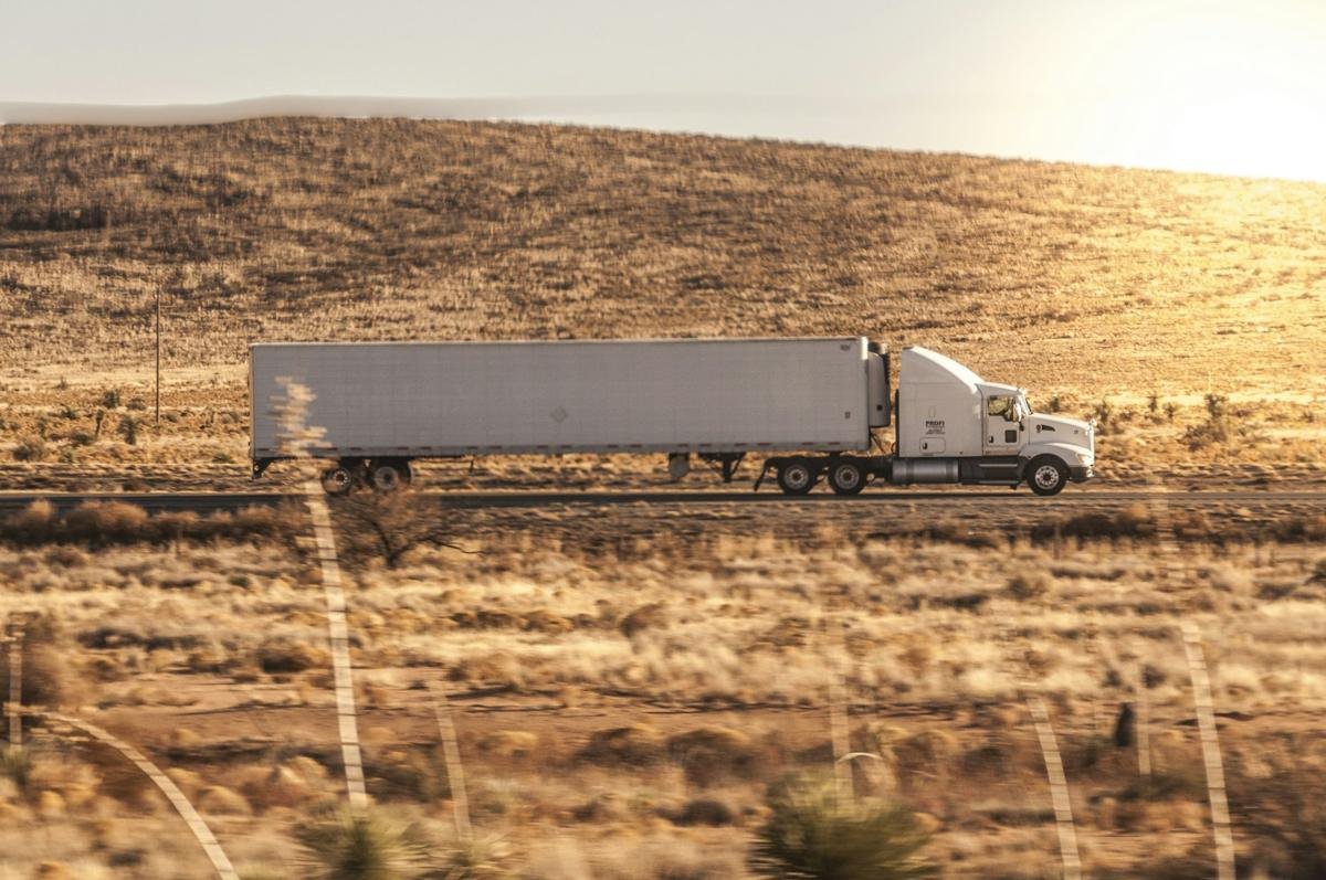 White tractor and dry van crossing open prairie